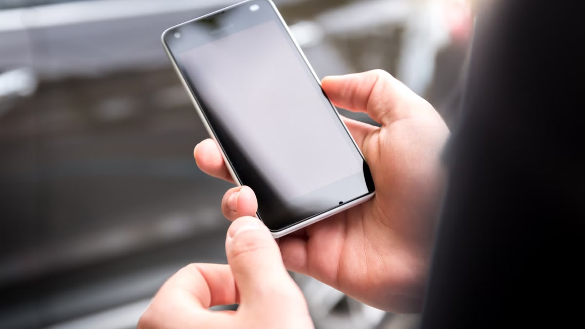 Close-up of hands holding a smartphone outdoors during the day.